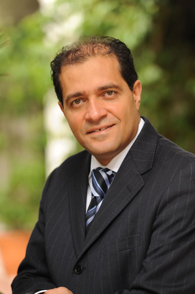 A man in a suit and tie, Dr. Youram Nassir looks directly at camera.